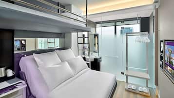 Ein modernes Hotelzimmer mit Bett, Schminktisch, Dusche und Blick auf die Stadt.