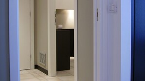 Un pasillo con una puerta que da a una habitación, un interruptor de luz y un termostato en la pared.