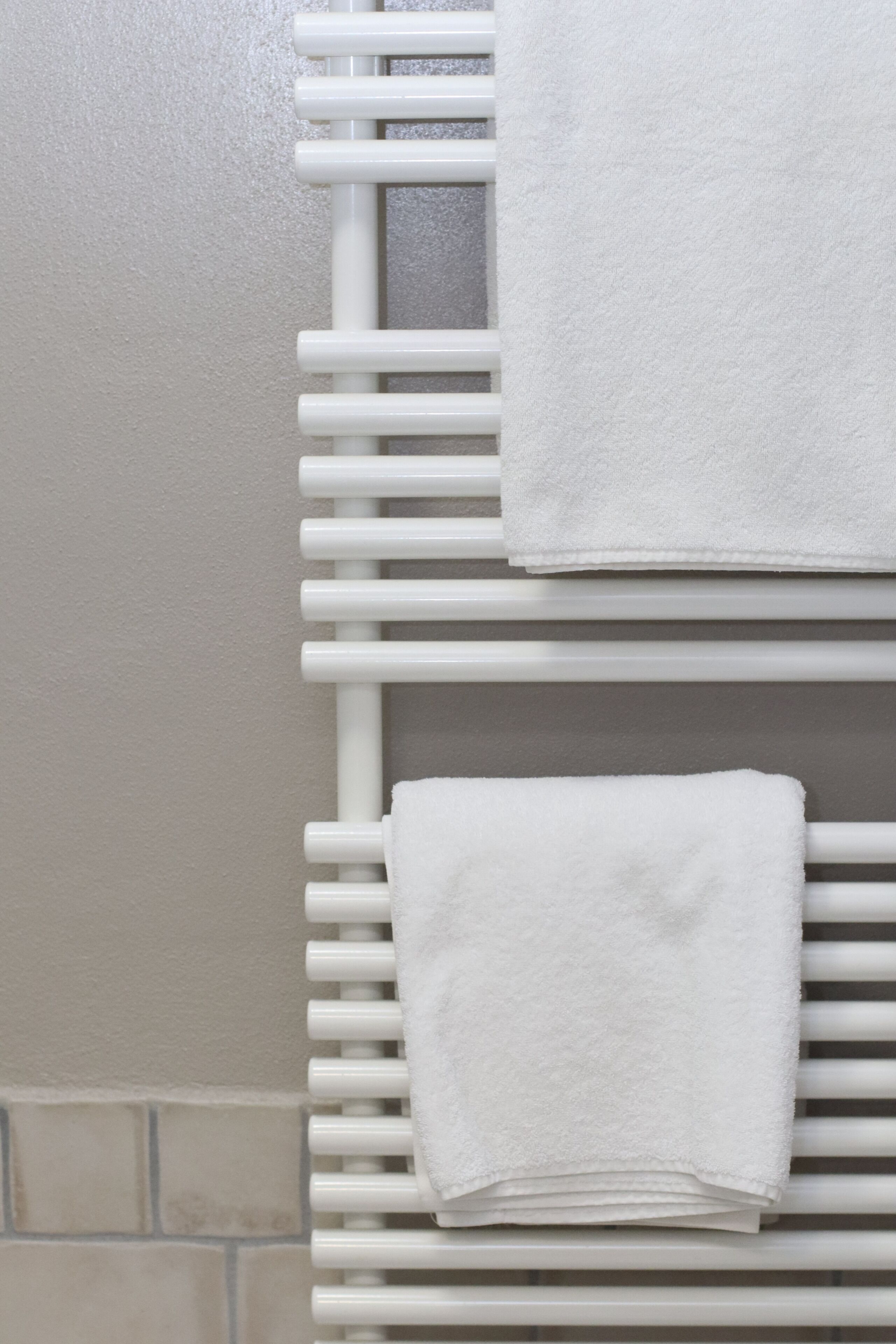 Μια λευκή κρεμάστρα για πετσέτες, πάνω στην οποία είναι διπλωμ ένες δύο πετσέτες.