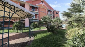 Un hotel con fachada roja, balcones con toldos a rayas y una palmera en primer plano.