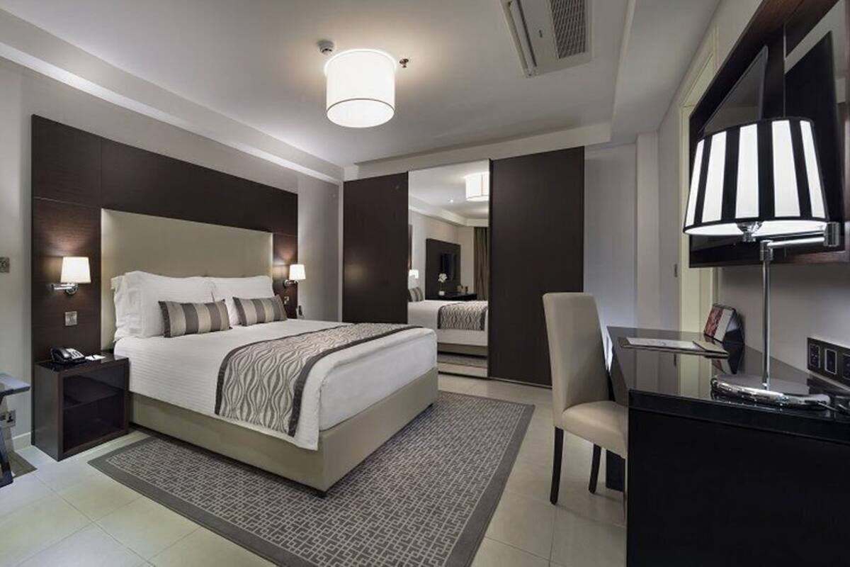 Une chambre d’hôtel moderne avec un grand lit, des tables de chevet, un bureau et une chaise.