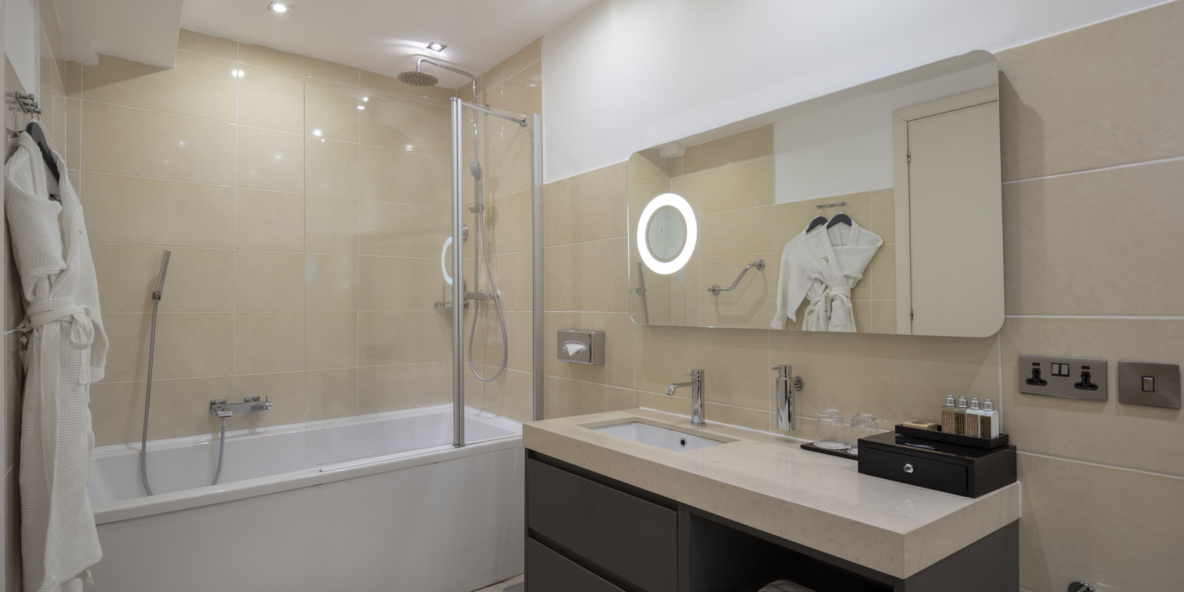A modern bathroom with a bathtub, a shower, a sink, and a vanity.