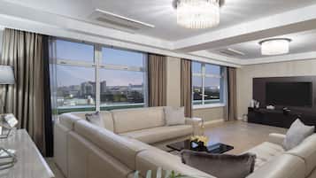 A modern living room with a sofa set, a TV, and a large window offering a city view.