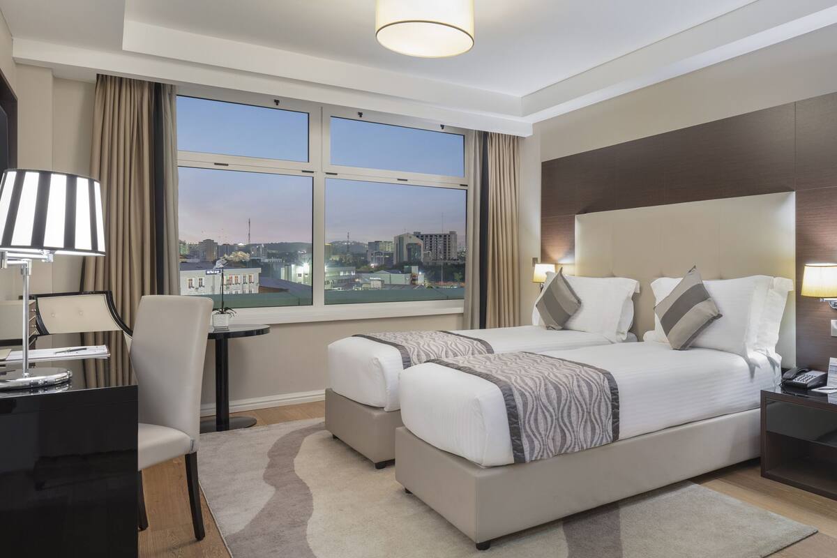 Une chambre d’hôtel moderne dotée d’un grand lit, d’un bureau, d’une chaise, d’une télévision et offrant une vue sur la ville.