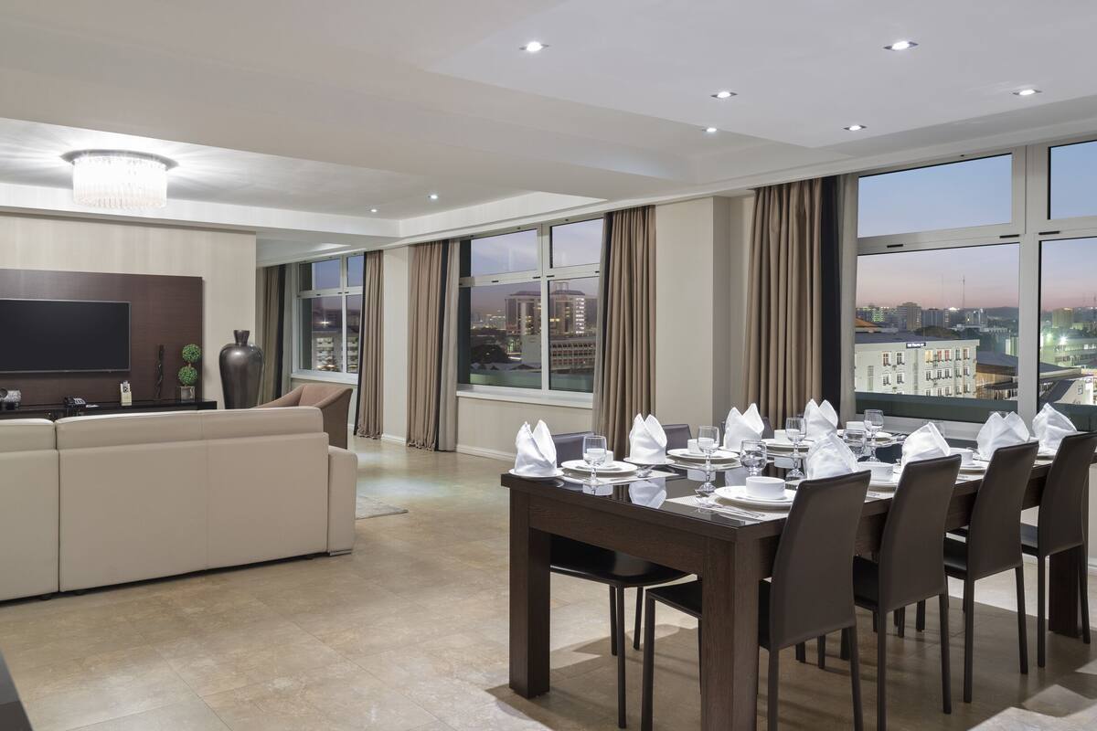 Un salon moderne avec un coin repas, de grandes fenêtres et une vue sur la ville.