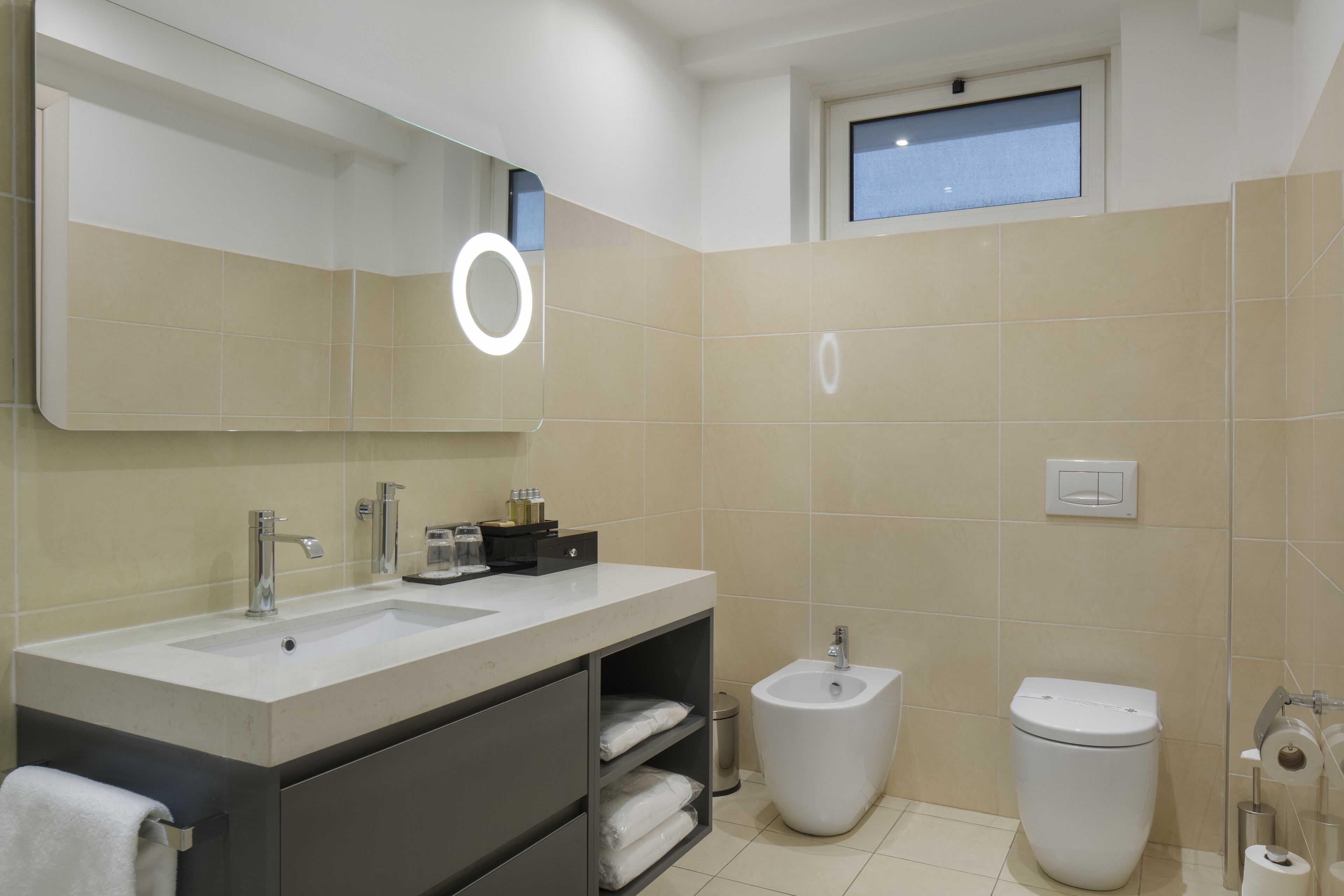 A modern bathroom with two sinks, a bidet, and a toilet.