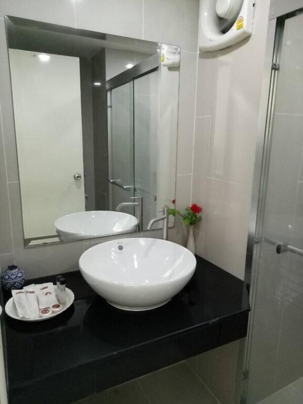 Un baño moderno con un espejo grande, dos lavamanos, una encimera negra y una zona de ducha.