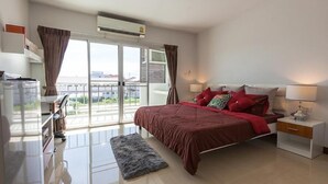 A modern bedroom with a large bed, a nightstand, a dresser, and a window with curtains. - Taweesuk Residence (Samut Sakhon)
