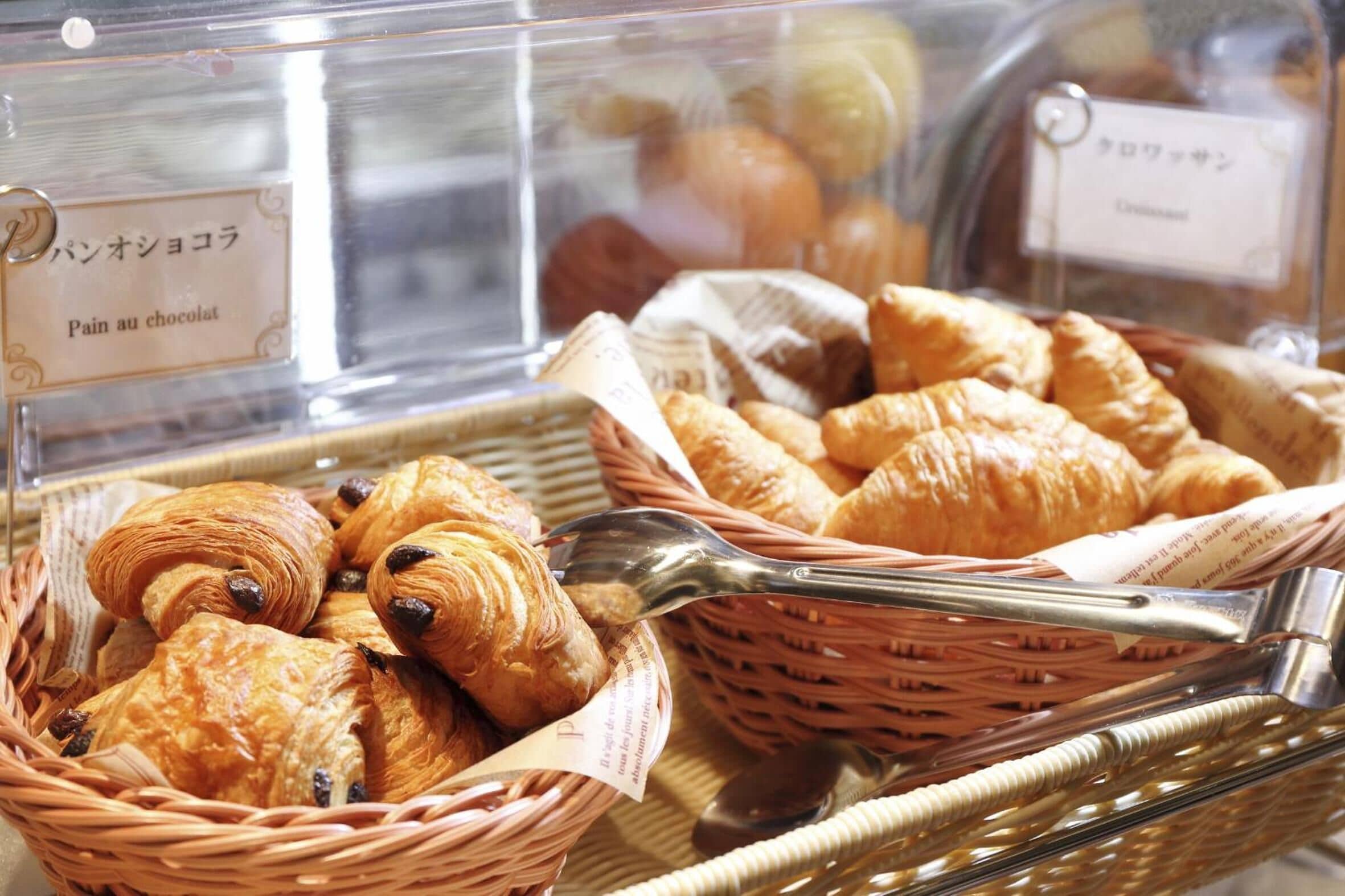 A bakery display with various pastries, including croissants and pain au chocolat, in wicker baskets.