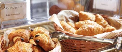 A bakery display with various pastries, including croissants and pain au chocolat, in wicker baskets.