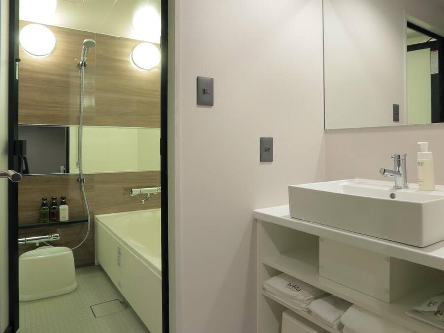 Un baño moderno con ducha de vidrio, lavamanos blanco y un espejo grande.