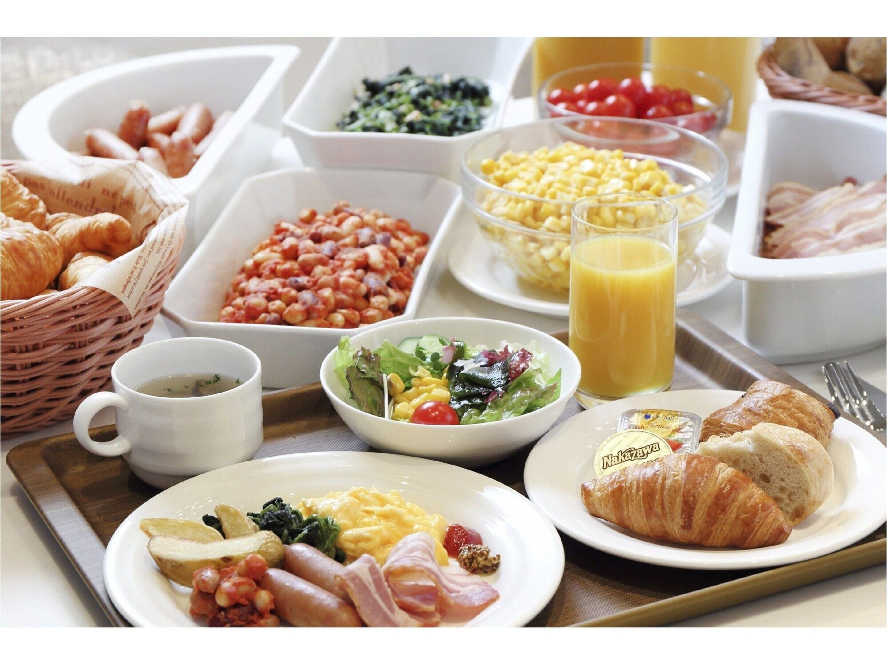 Un bufé de desayuno con diversas opciones de comida, incluyendo huevos, salchichas y pasteles.