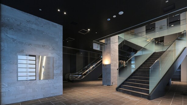 A modern interior with a marble wall, an escalator, and a staircase. - Kisarazu Washington Hotel (Kisarazu)