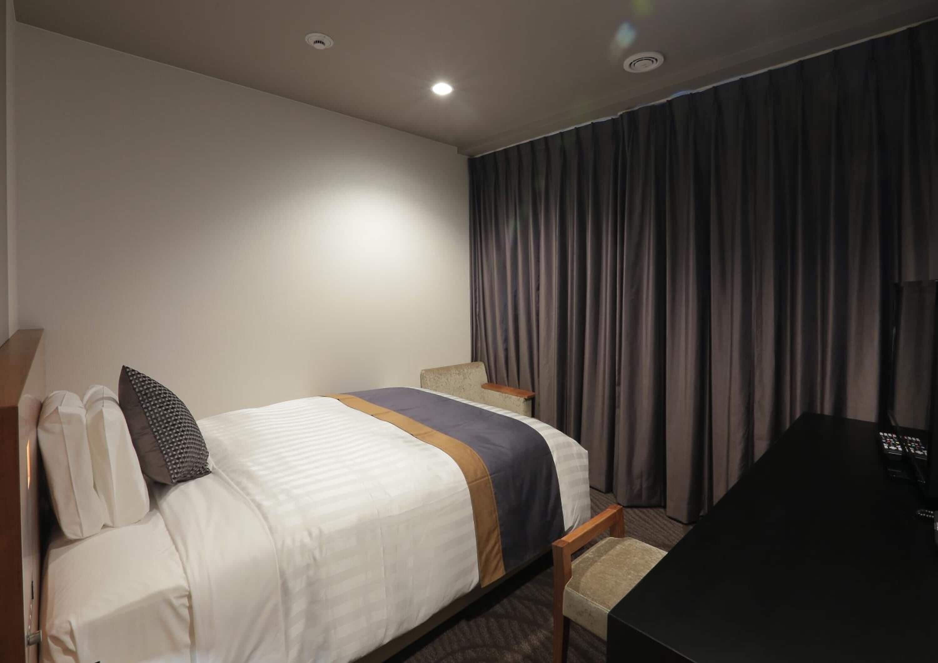 A hotel room with a bed, a desk, and a chair.