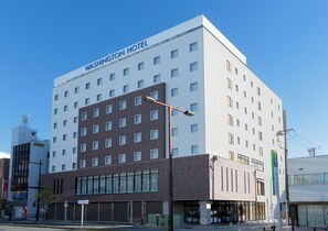 Monikerroksinen hotelli, jossa on moderni muotoilu ja jonka katolla on suuri, selkeästi näkyvä kyltti, jossa lukee: ”Washington Hotel”.