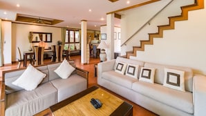 Ein geräumiger Wohnbereich mit einer Couch, einem Couchtisch und einer Treppe.