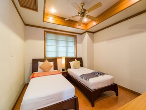 A bedroom with two single beds, a ceiling fan, a window with blinds, and a wooden floor. - 3 Bedroom Villa Beach Front Resort TG12 (Koh Samui)