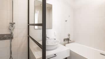 A modern bathroom with a white sink, mirror, and bathtub.