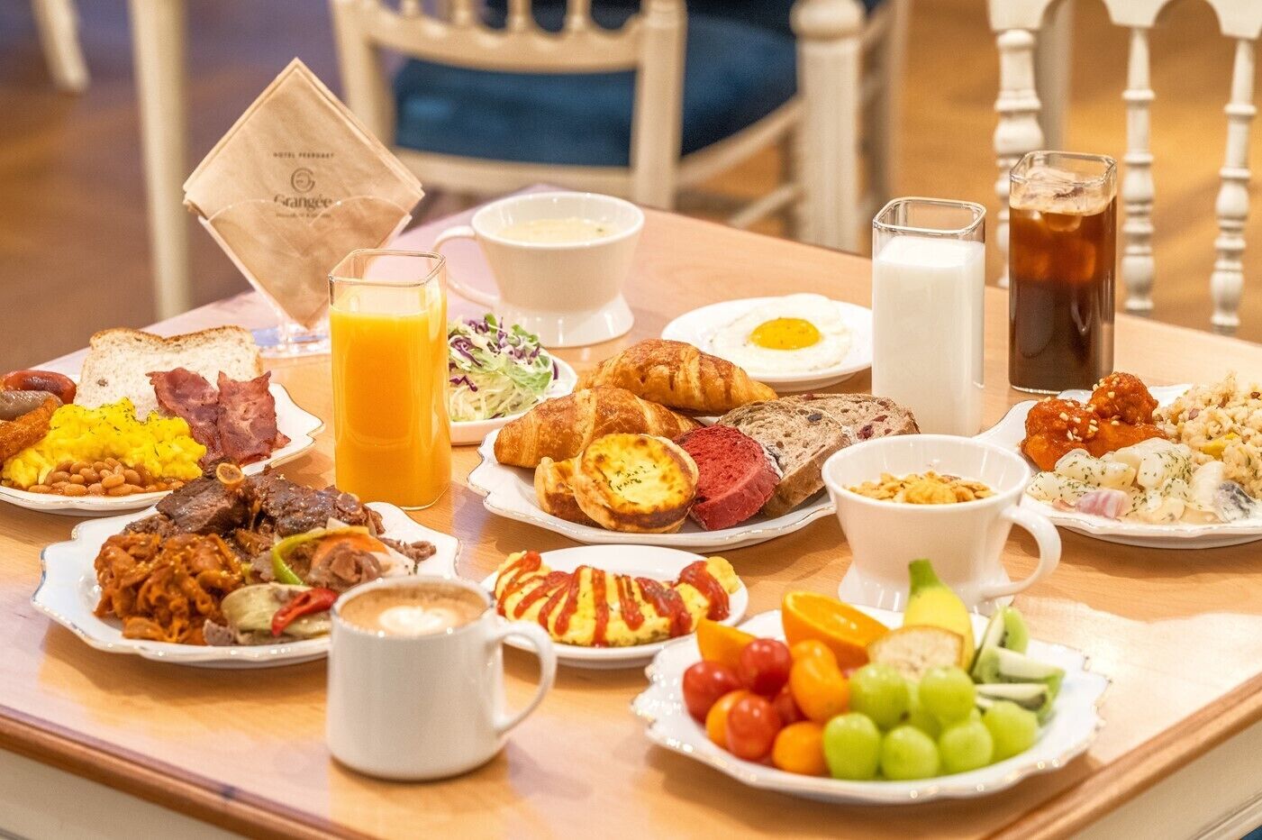 A breakfast buffet with various dishes, drinks, and a coffee mug on a table.