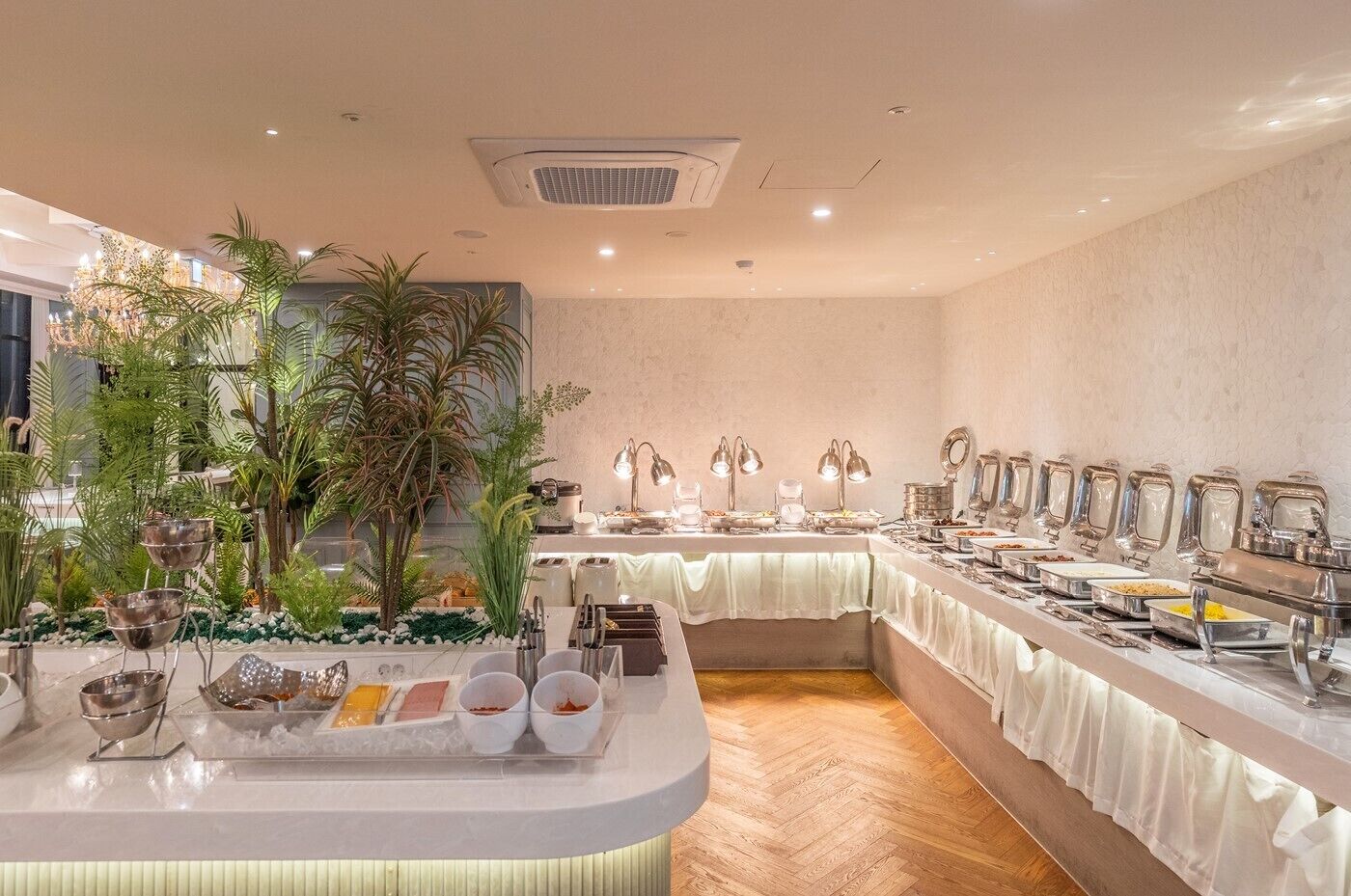 A buffet setup with a variety of food items and a decorative plant arrangement.