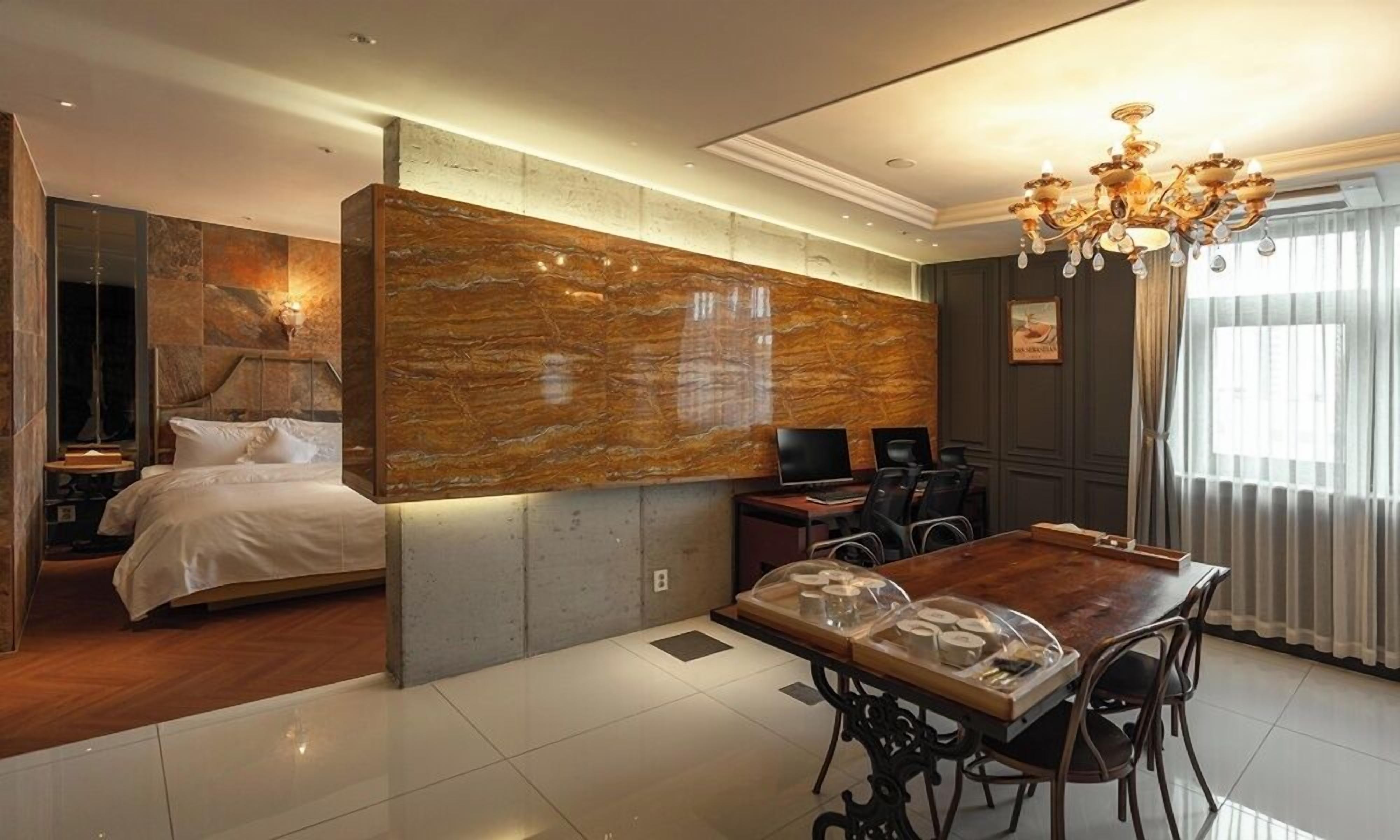 Una habitación de hotel con una cama, un escritorio, una araña y una gran pared de mármol.
