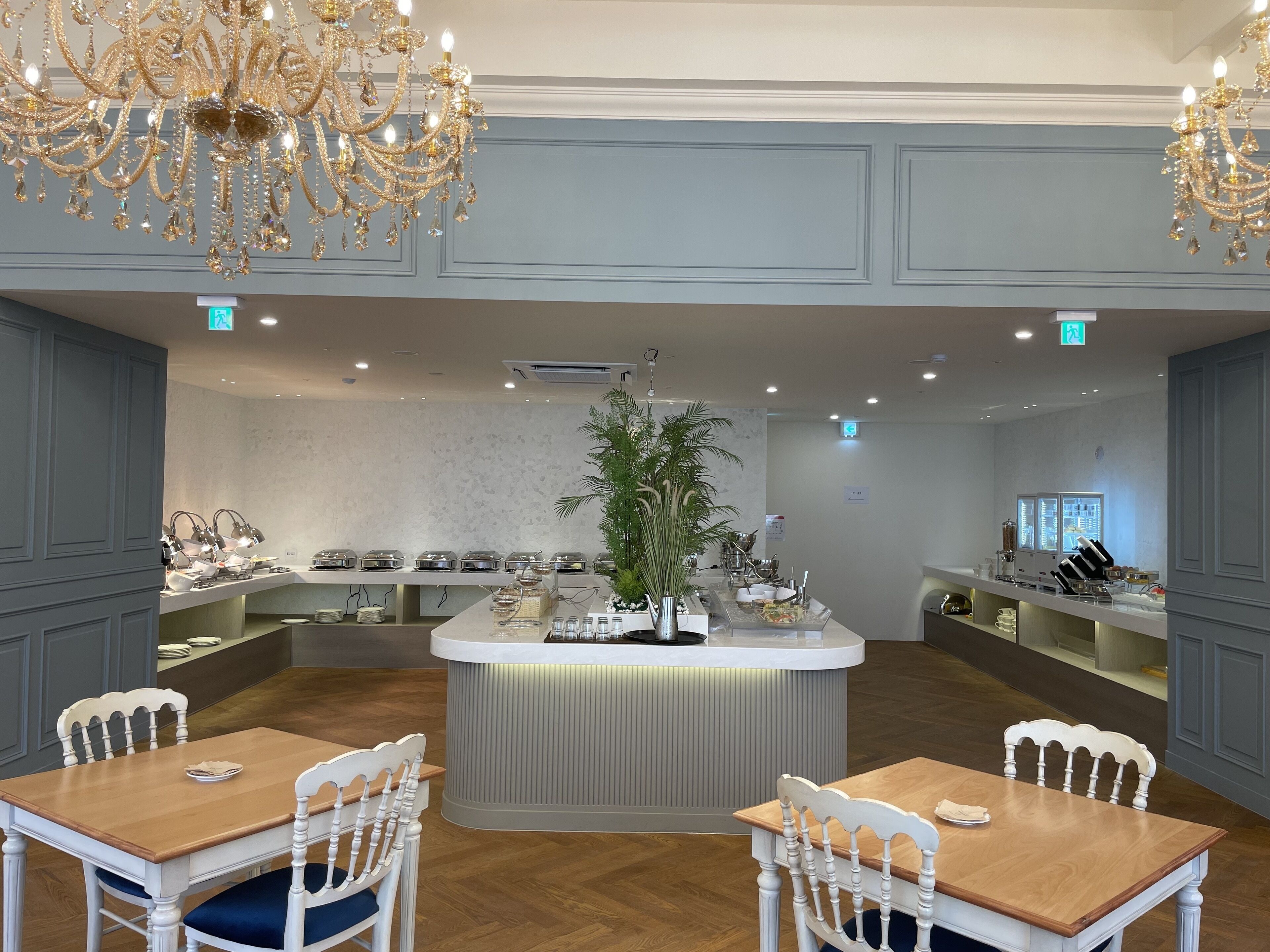 A restaurant with a central island, white chairs, and a chandelier.