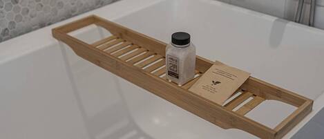 A wooden tray with a bottle and a card on a bathroom sink.