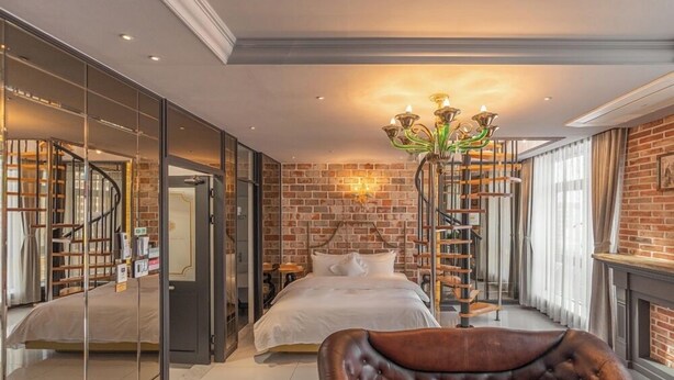 Une chambre à coucher avec un lit, un lustre, un mur en briques et un escalier.
