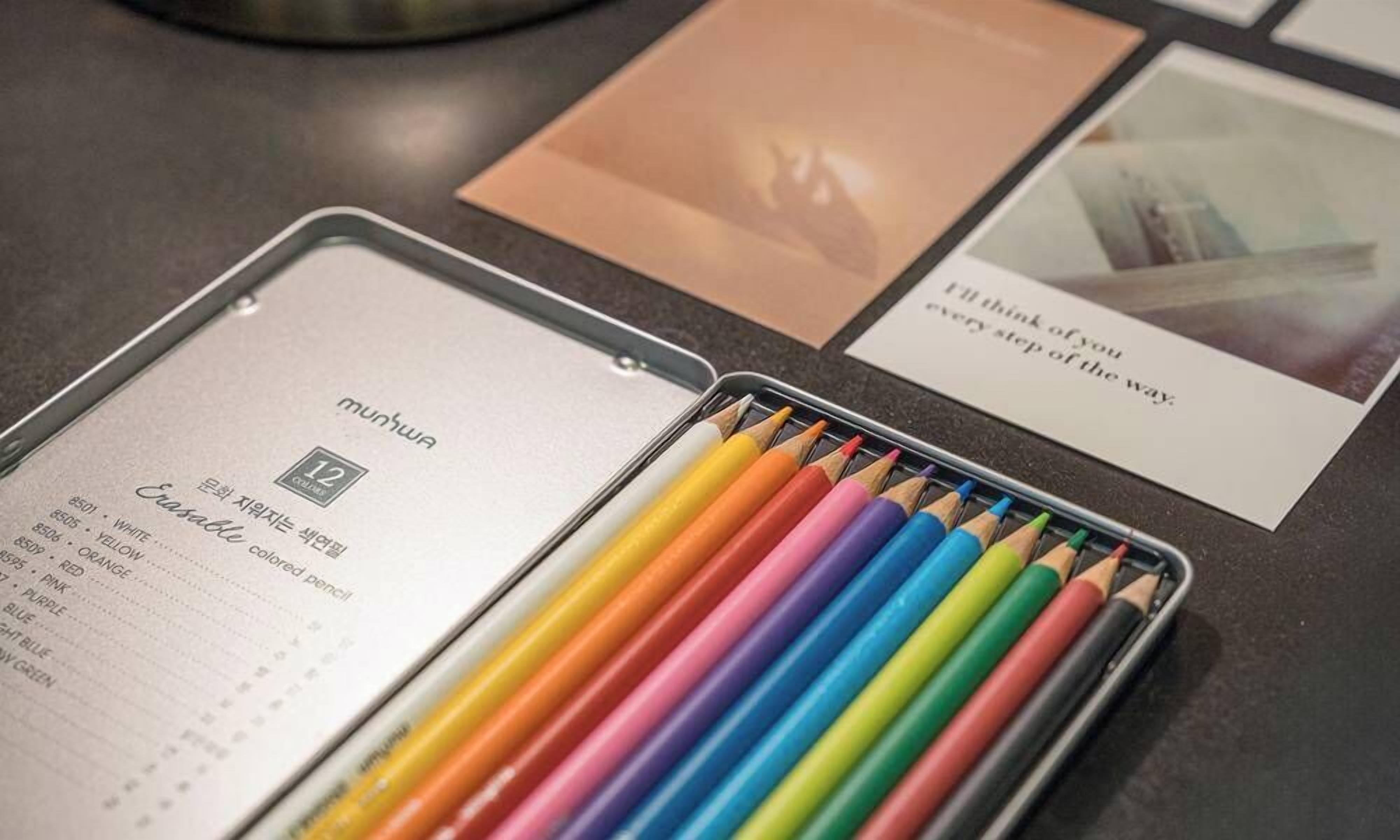 Un bote de lápices de colores, una libreta con una lista de colores y dos tarjetas con texto.