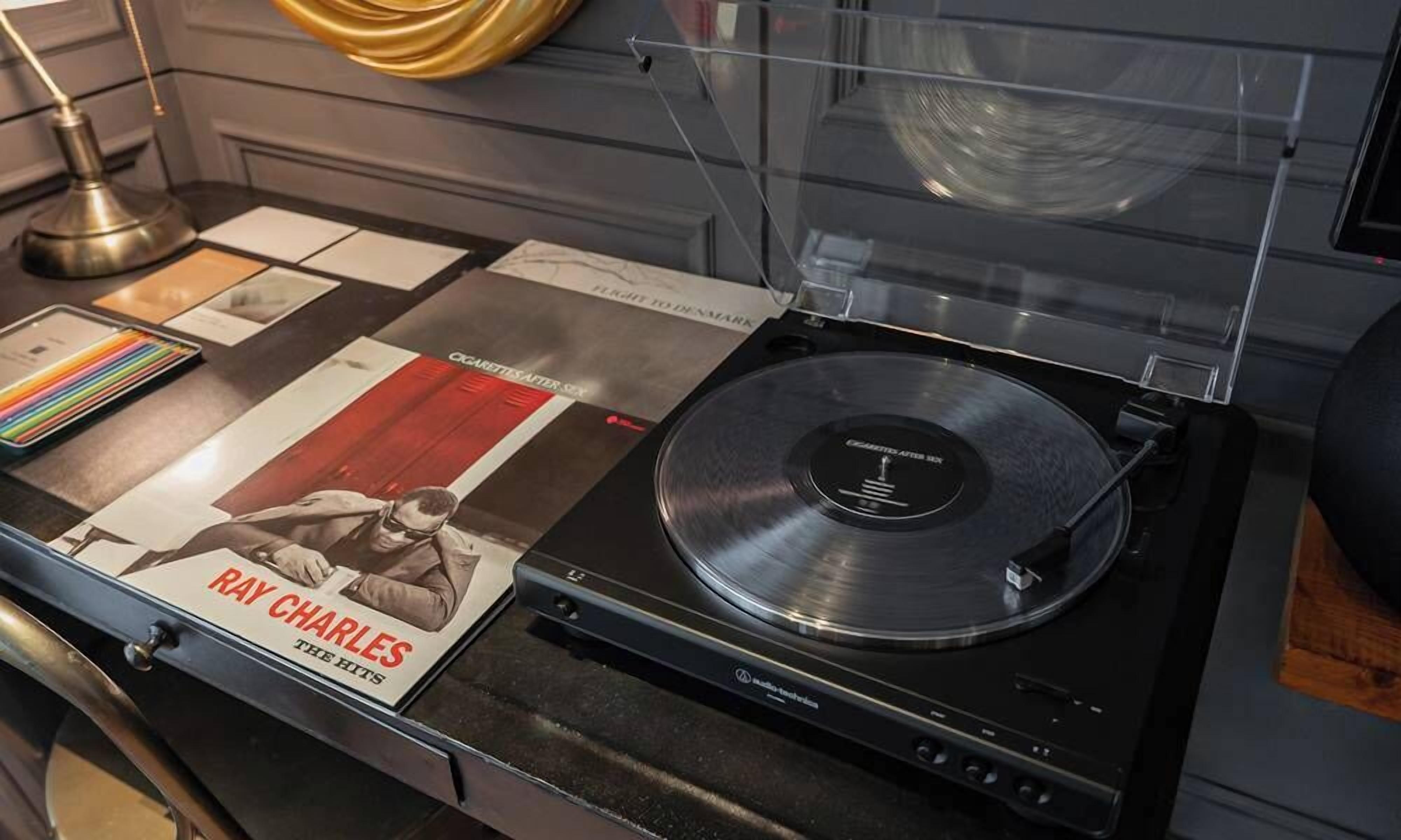 Une platine vinyle avec un disque, un magazine dont la couverture présente Ray Charles, et une lampe.