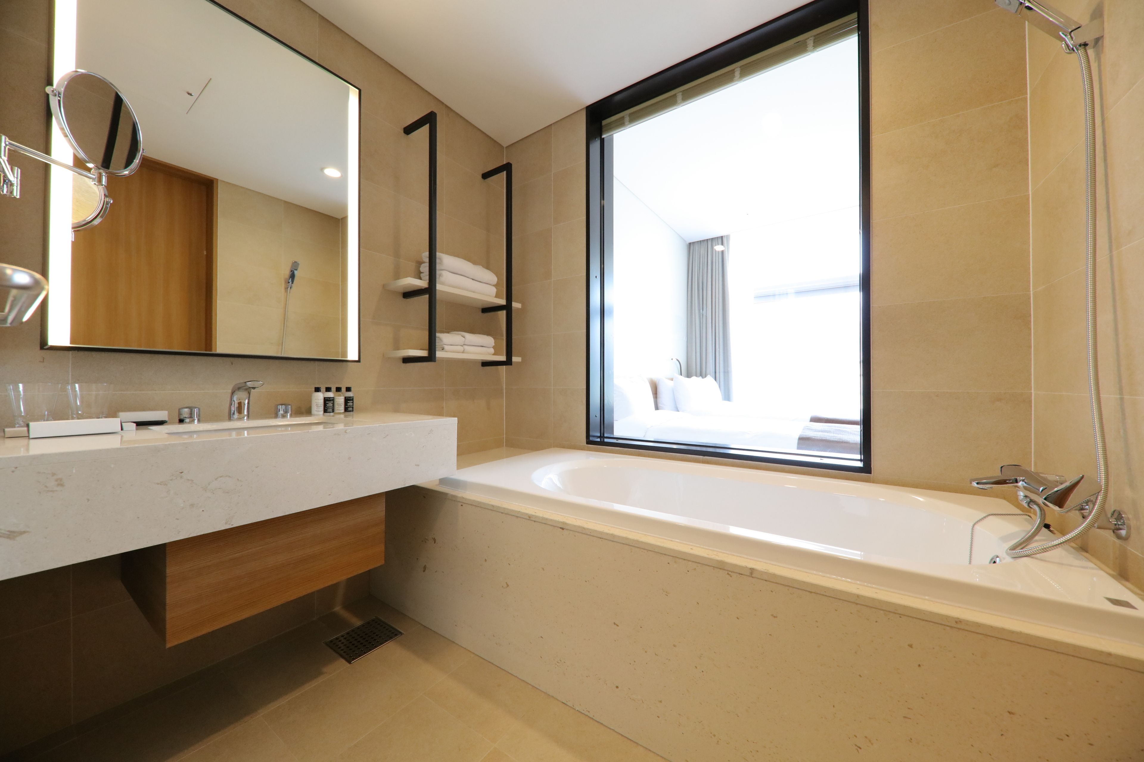 A modern bathroom with a large bathtub, a vanity with a mirror, and a window providing a view of the outside.