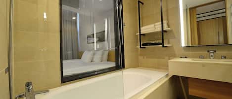 Un baño moderno con una bañera grande, cabina de ducha de vidrio y tocador de madera.