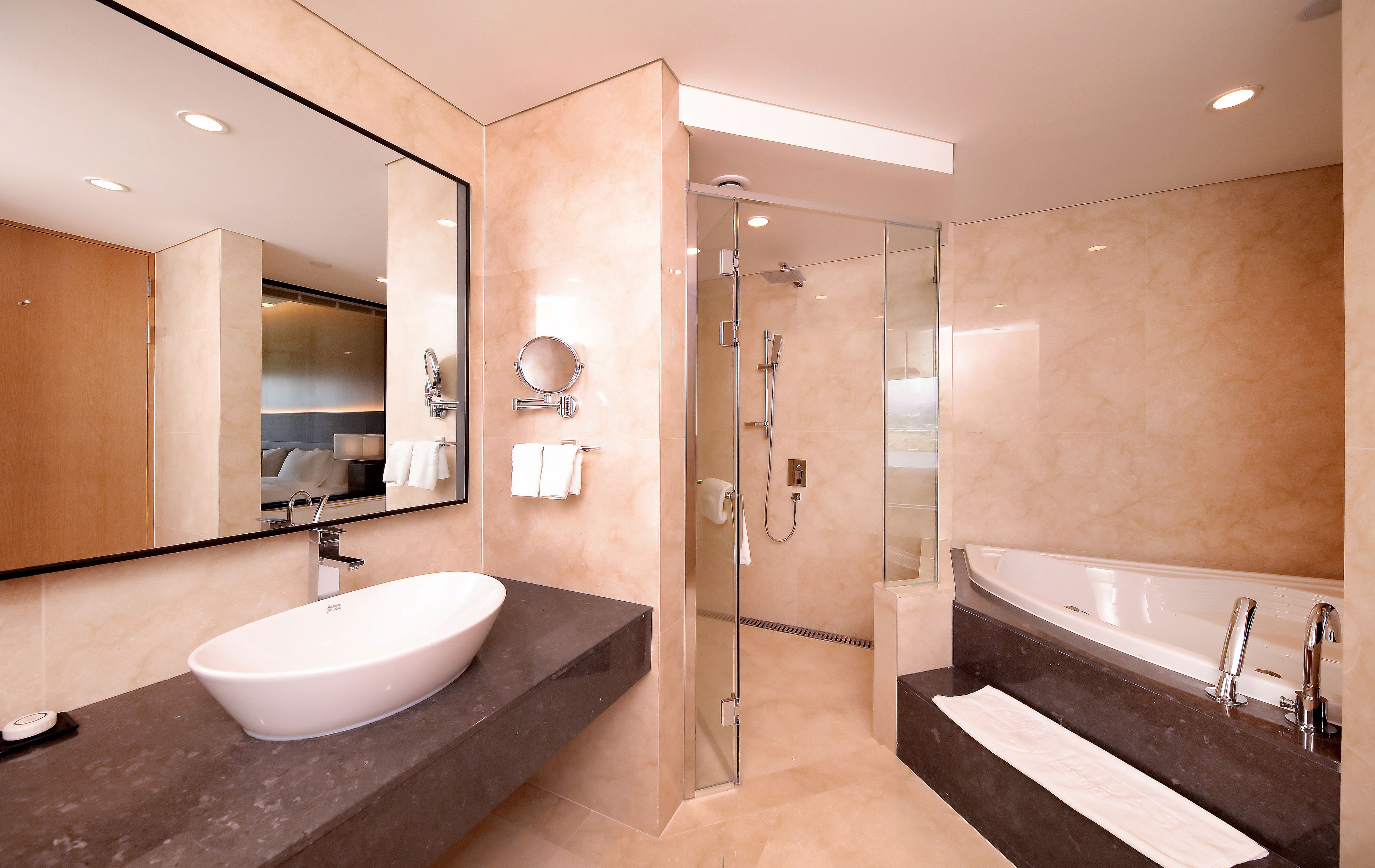 Een moderne badkamer met een ruime wastafel, een badkuip en een douche met glazen wanden.
