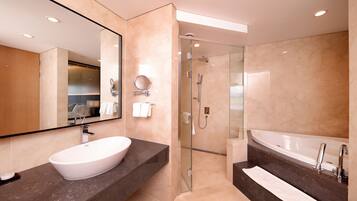 Une salle de bain moderne dotée d’un grand lavabo, d’une baignoire et d’une douche à parois de verre.