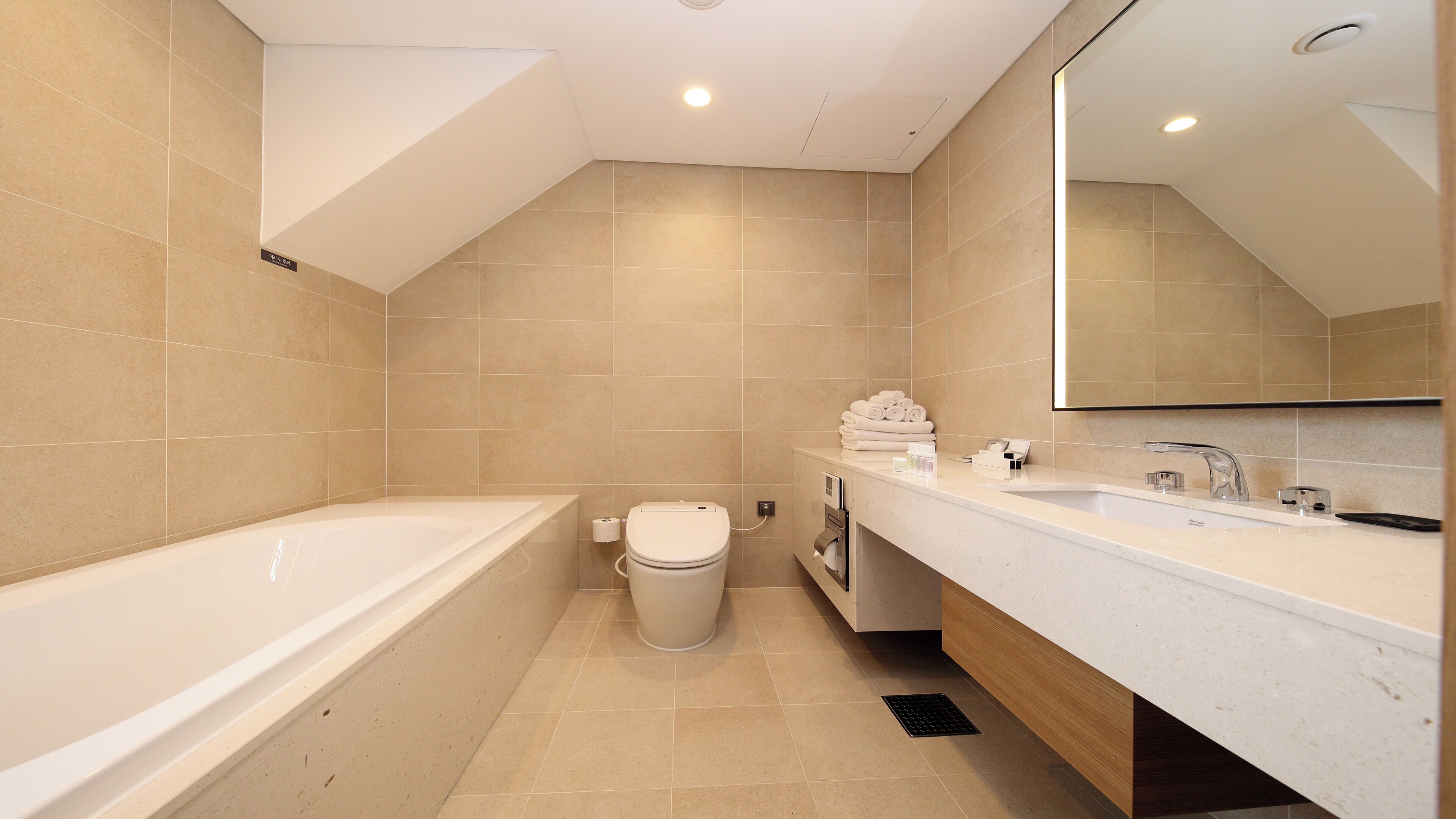 A modern bathroom with a bathtub, toilet, vanity with a mirror, and a towel rack.