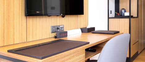 A modern room with a wooden desk, a mounted flat-screen TV, and a chair.