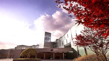 Een modern hotel met een opvallende glazen gevel, een aangelegde entree en een heldere lucht.