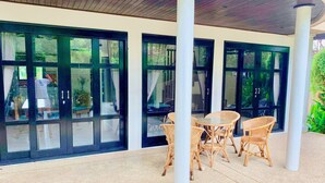 Un espace extérieur aménagé en terrasse, avec des meubles en osier et de grandes portes vitrées donnant sur un jardin.