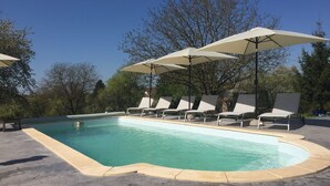 Piscina con sillones de descanso y sombrillas.
