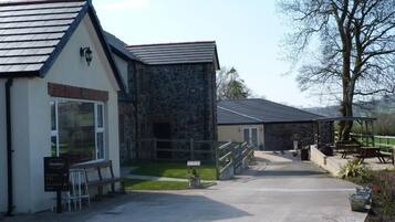 A building with a stone facade, a wooden bench, and a paved entrance.
