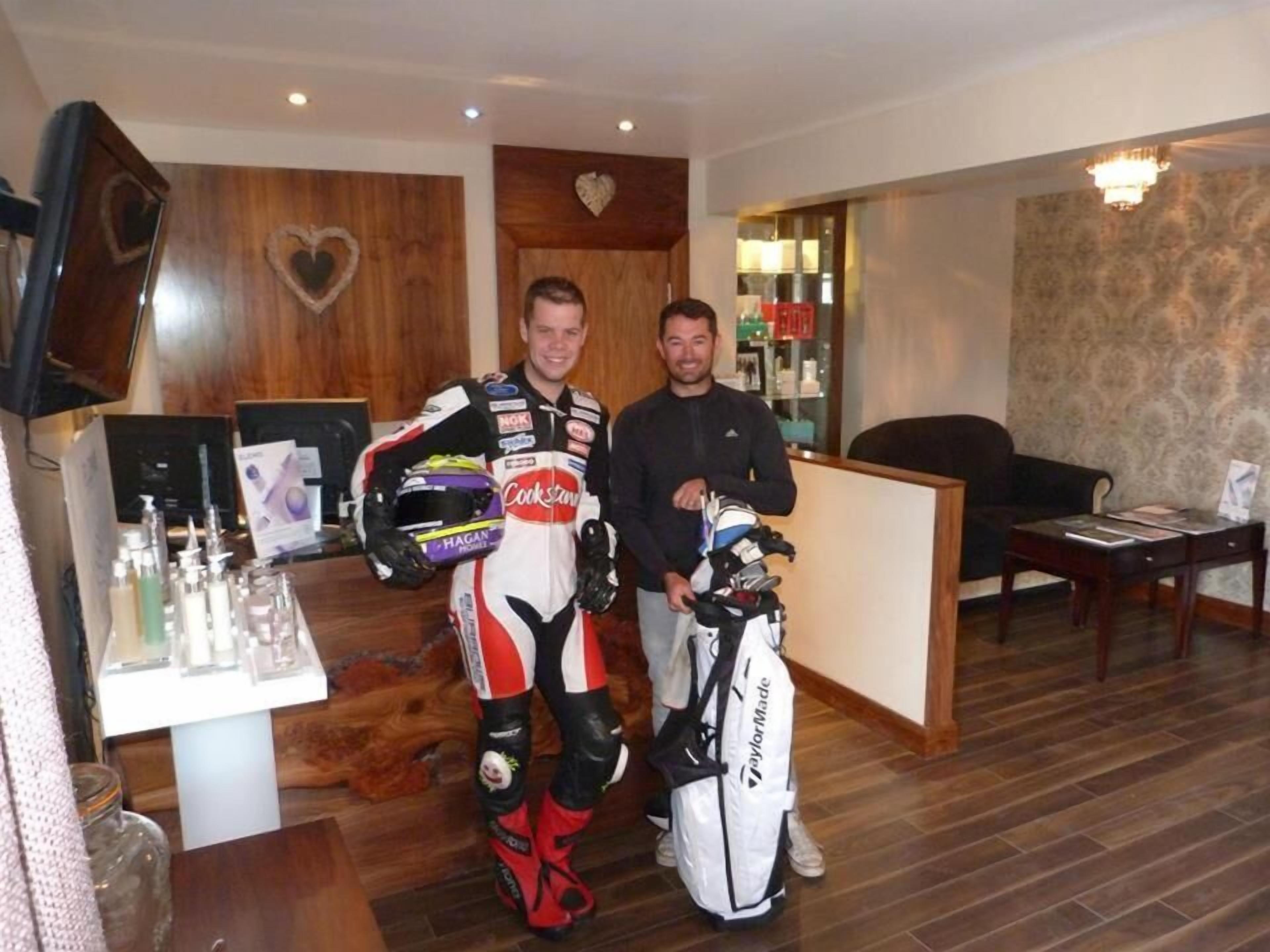 A room with a wooden reception desk, a television mounted on the wall, and a table with various items including a golf bag.