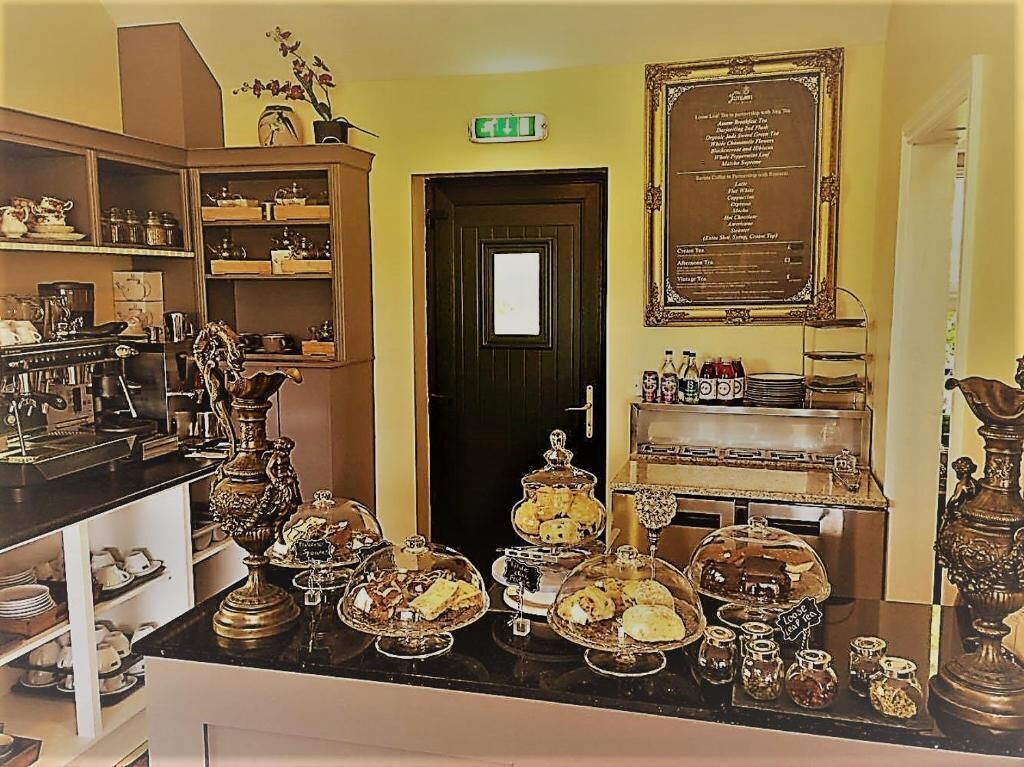 A room with a counter displaying various food items, a door with a sign, and a framed menu on the wall.