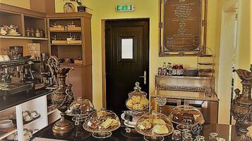 A room with a counter displaying various food items, a door with a sign, and a framed menu on the wall.