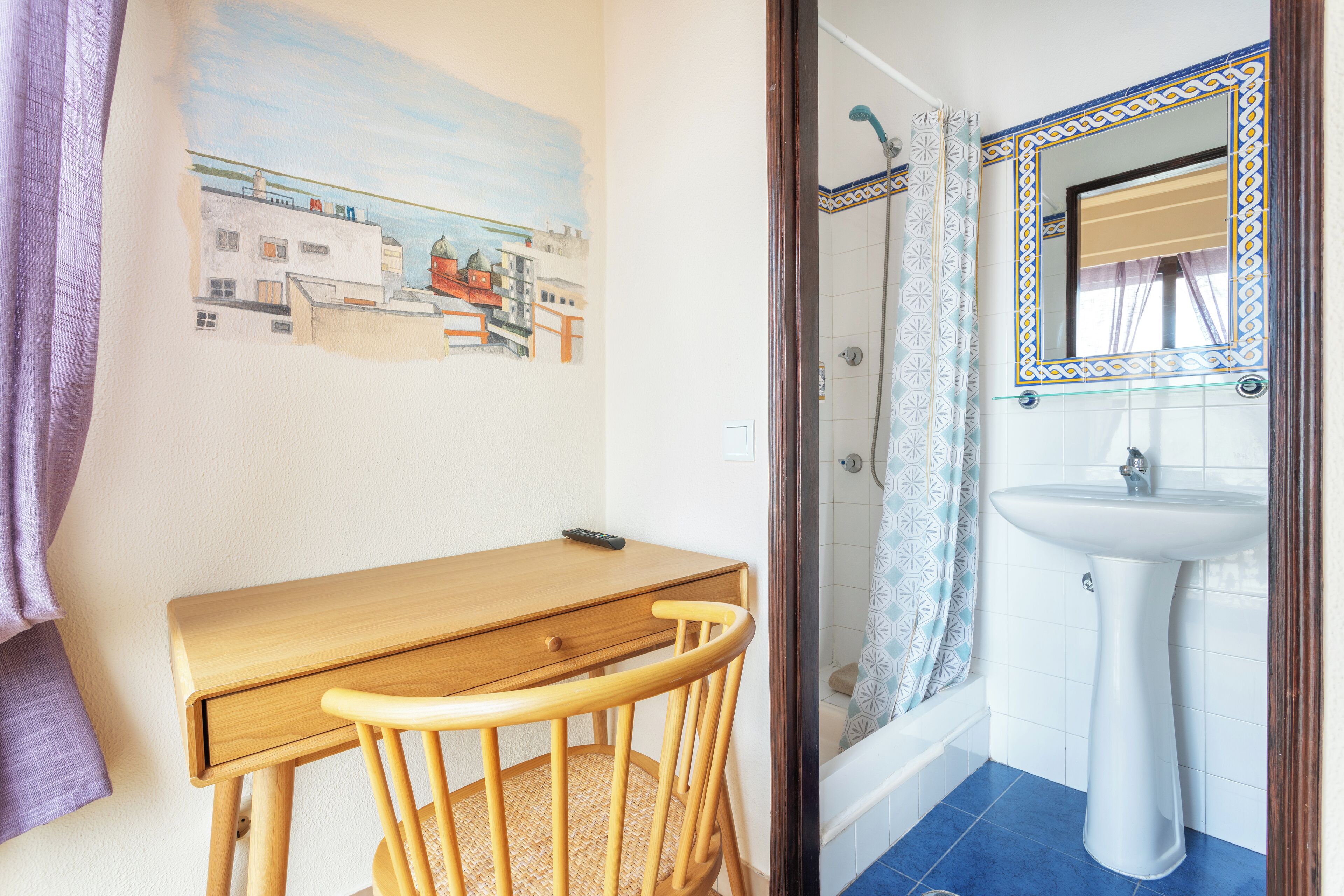 Une salle de bain avec une douche, un lavabo et une chaise en bois.