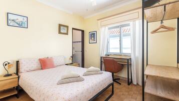 Ein Schlafzimmer mit Bett, Schreibtisch, Stuhl und Kleiderschrank.