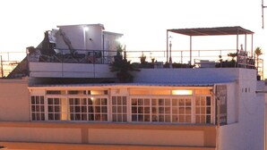 Un edificio de varios pisos con balcones, ventanas amplias y una terraza en la azotea.