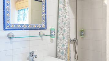 A bathroom with a white sink, a mirror with a blue frame, and a shower with a patterned curtain.