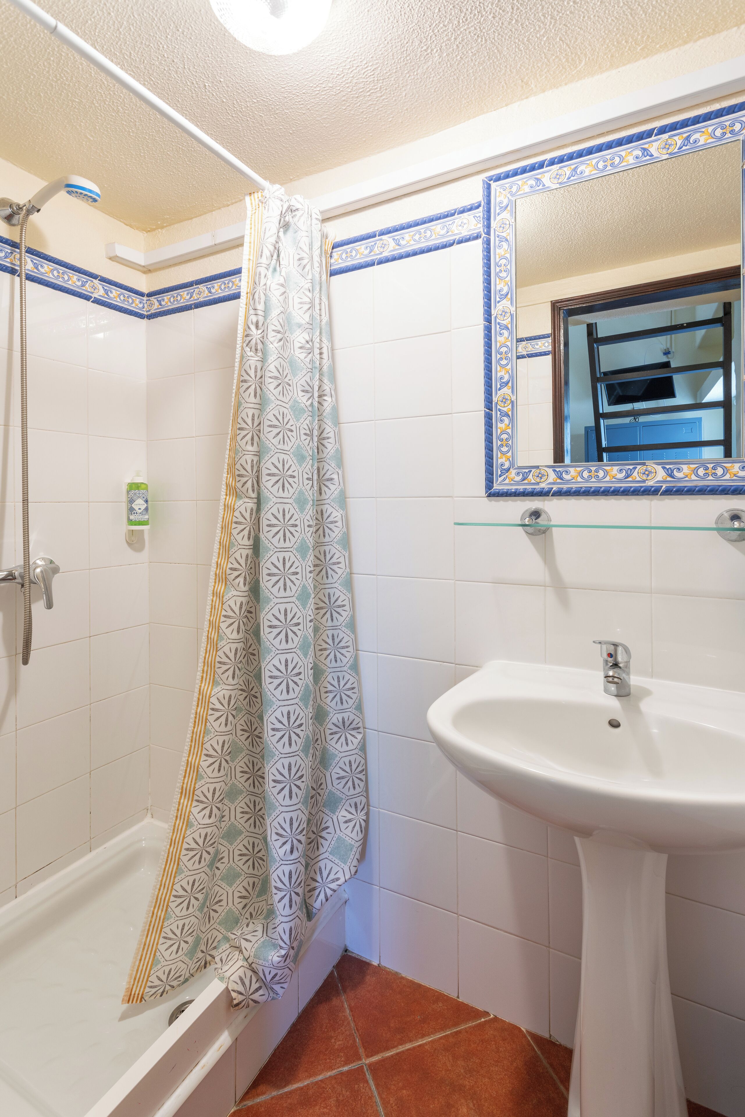 Un baño con ducha, lavabo y espejo.