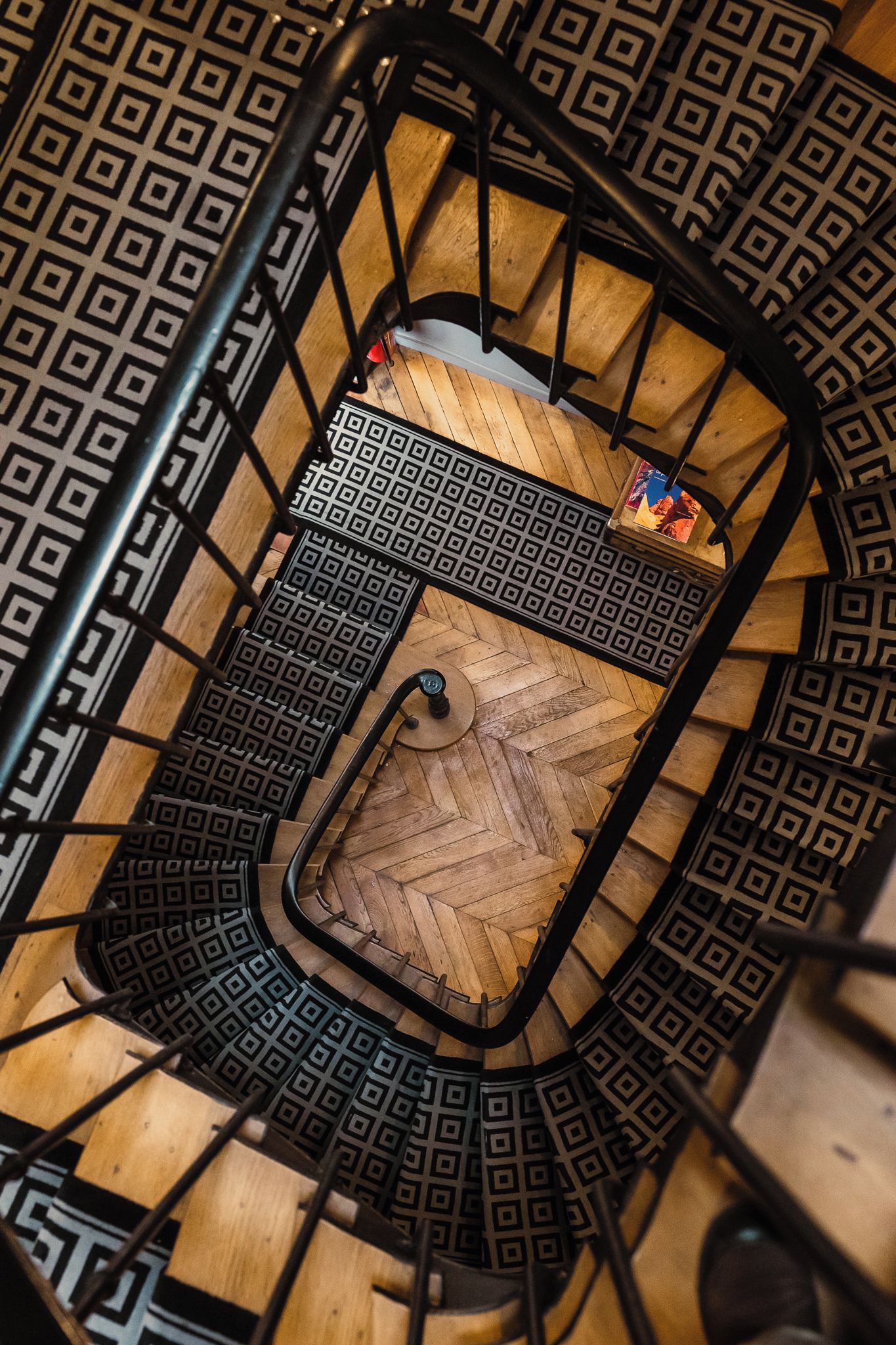 A spiral staircase with a geometric patterned floor and metal railings.