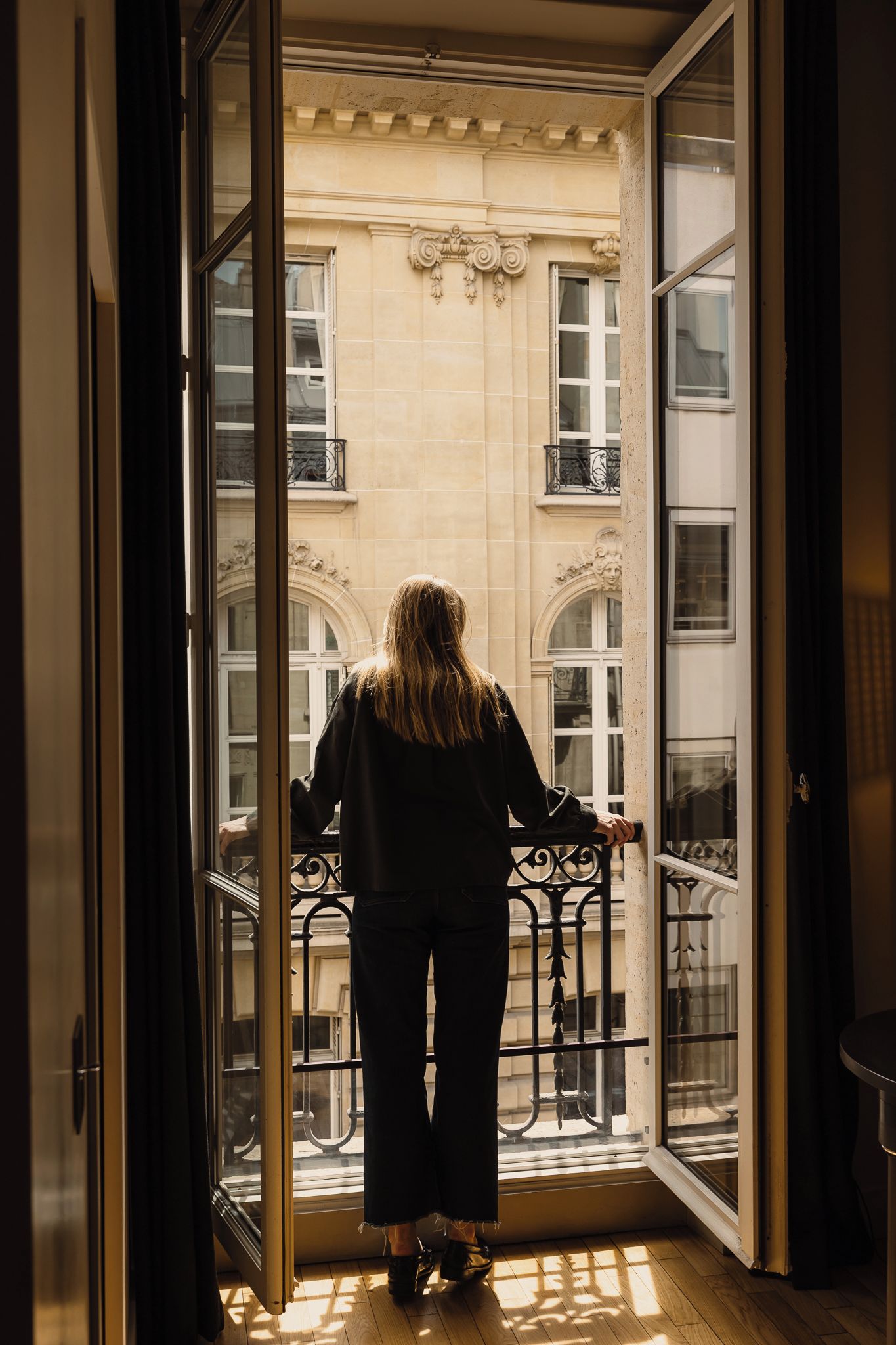 Une personne se tient sur un balcon, d’où l’on peut admirer la façade d’un immeuble.